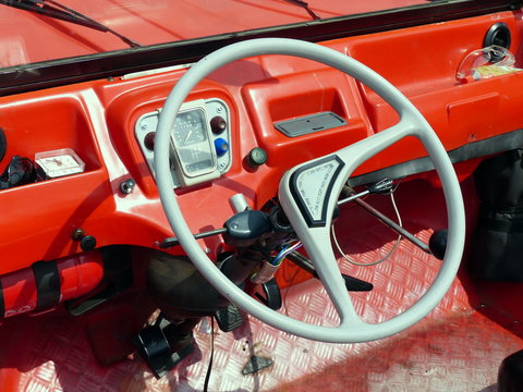 Spartanisches rotes Interieur mit Zweispeichenlenkrad eines franz&ouml;sischen Gel&auml;ndewagen der Siebzigerjahre im Sommer in Lage bei Detmold am Teutoburger Wald in Ostwestfalen-Lippe