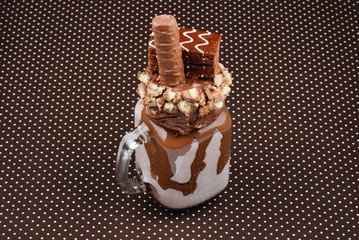 Chocolate extreme milkshake with brownie cake, chocolate paste and sweets. Crazy freakshake food trend. Copy space