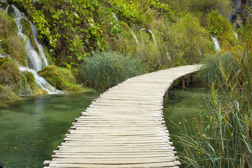 lonely wooden pathway and emerald lake with waterfall in Croatia