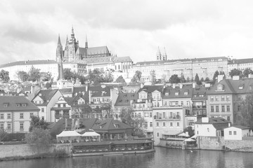 View of Mala Strana, St. Vitus Cathedral and Prague castle over Vltava river in black and white.