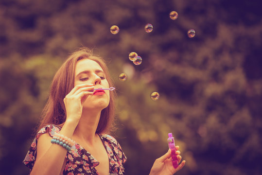 Woman blowing soap bubbles, having fun