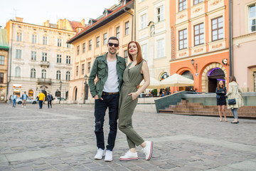 young beautiful couple of tourists stand in the square in the city of Krakow in Poland - obrazy, fototapety, plakaty