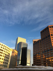 Fototapeta na wymiar Group of office buildings in the business district of Denver at sunrise. Warm light shining on skyscrapers in downtown Denver Colorado USA. Blue sky with wispy clouds. Vertical.