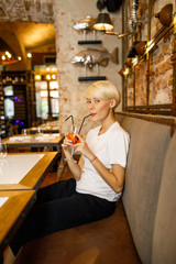 young beautiful blonde girl drinks cocktail at restaurant
