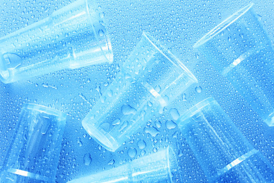 Disposable plastic cup with water drops on a blue background