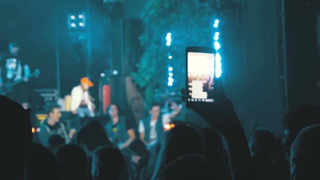 People at a Rock Concert are Broadcasting Live on the Social Network using Smartphone. People at Music Rock Festival Taking Photos or Recording Video with Mobile Phones. Fan person filming rock