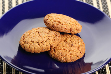 Oat biscuits on a dark background. Cookies in a blue plate. Healthy and delicious food.