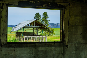 Fototapeta na wymiar Seeing shed outside barn window with field background