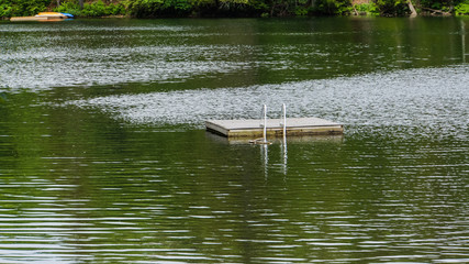 wooden swim raft with ladder floating on a lake  