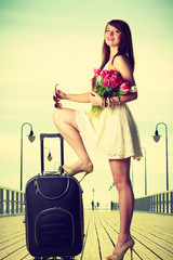 Fototapeta na wymiar Woman standing one leg on suitcase, summertime