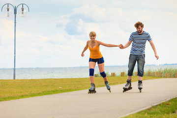 Obraz premium Young couple on roller skates riding outdoors