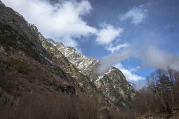 Горный пейзаж. Вершины в белых облаках, Красивый вид на живописное ущелье, панорама с высокими горами. Природа Северного Кавказа, отдых в горах
