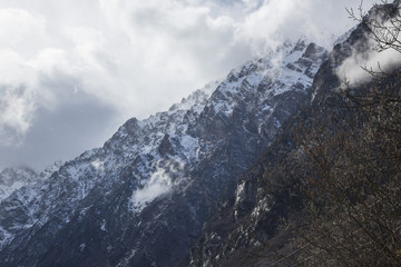 Горный пейзаж. Вершины в белых облаках, Красивый вид на живописное ущелье, панорама с высокими горами. Природа Северного Кавказа, отдых в горах