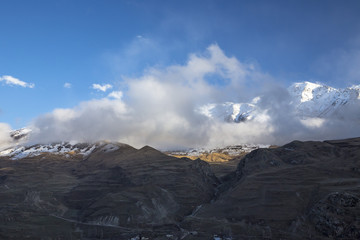 Obraz na płótnie Canvas Горный пейзаж. Вершины в белых облаках, Красивый вид на живописное ущелье, панорама с высокими горами. Природа Северного Кавказа, отдых в горах
