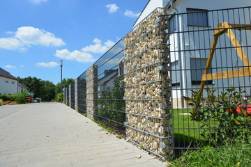 Moderner Sichtschutzzaun aus mit Naturstein gefüllten Gabionen aus verzinktem Stahlgitter um ein...