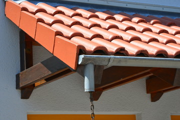 Mit Ziegeln gedecktes Fachwerk-Holz-Vordach mit Dachrinne und freiem Ablauf an einem Wohnhauseingang