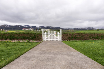 Closed white wooden gate with mountains in the background