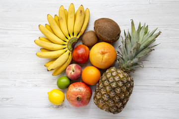 Set of fresh tropical fruits on a white wooden surface, top view. From above.