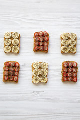 Toasts with peanut butter, fruits and chia seeds on a white wooden table, top view. Healthy breakfast. Copy space.