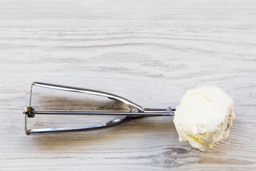 Ice cream in ice cream scoop on a white wooden table, top view. Copy space.