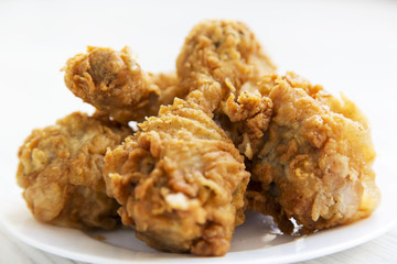 Fried chicken drumsticks on a white plate, close-up.
