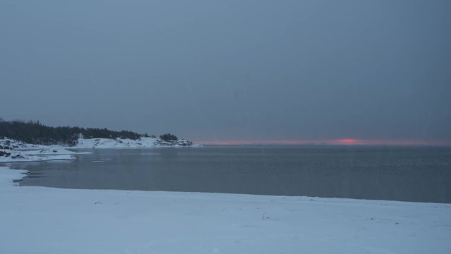 Timelapse of sunrise during light snow on snowy beach in Hanko, Finland