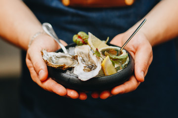 gorgeous oysters on a dark plate in men's hands.