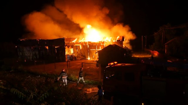 Firefighters In Front Of A Burning Fire