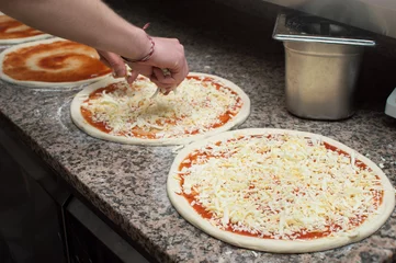 Cook in the kitchen putting the ingredients on the pizza. Pizza concept. Production and delivery of food.