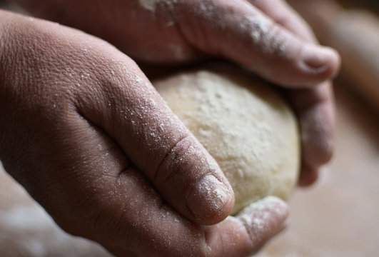 Old man holding a dough. Cook preparing raw dough for pizza. Handmade.