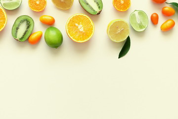 Fruit background. Summer concept. Colorful fresh citrus fruit on a light pastel yellow background table. Orange, tangerine, lime, kiwi. Flat lay, top view, copy space 