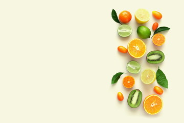 Fruit background. Summer concept. Colorful fresh citrus fruit on a light pastel yellow background table. Orange, tangerine, lime, kiwi. Flat lay, top view, copy space 
