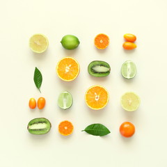 Fruit background. Summer concept. Colorful fresh citrus fruit on a light pastel yellow background table. Orange, tangerine, lime, kiwi. Flat lay, top view, copy space 