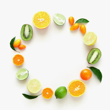 Fruit background. Summer concept. Colorful fresh citrus fruit on a light pastel yellow background table. Orange, tangerine, lime, kiwi. Flat lay, top view, copy space 