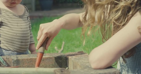 Little toddler boy watching his mother dig in the garden