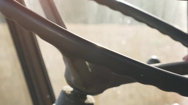 Driving a thresher truck in golden wheat field, close up on driver's hands on the wheel. Tractor farming.