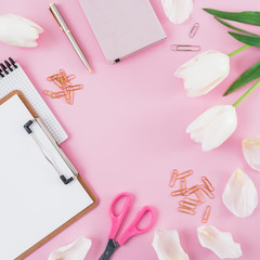 Frame with tulips flowers, mug of coffee, clipboard, clips and glasses on pink background. Blogger concept with copy space. Flat lay, top view.