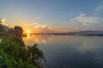 Sunrise view from Songkhla lake, southern Thailand with blue sky, mountain and small fisherman hut in the middle.