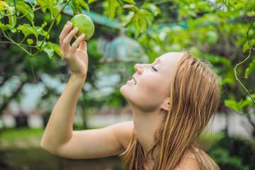 Young woman smelling the passion fruit in the garden