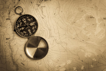 Manual compass on a topographical map with vintage look