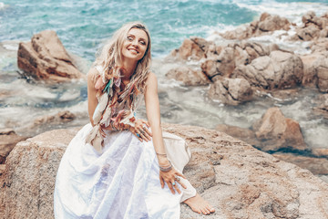 cheerful young boho style woman in white dress on stone beach © zolotareva_elina