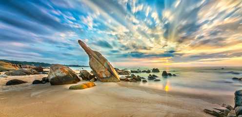 Fototapeta premium Volcanic rocks beach in sunrise with dramatic sky, below reefs are interspersed waves undulating smooth real welcome new day beautiful