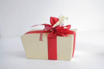 Beige square gift box with red bow on white background