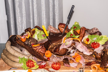 Meat Food tray with pieces of sliced ham, sausage tomatoes and vegetable cutting sausage cured meat on celebratory table