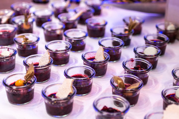 Closeup many dessert jar rowed up on buffet table with fresh fruits jelly and cream