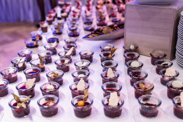 Closeup many dessert jar rowed up on buffet table with fresh fruits jelly and cream