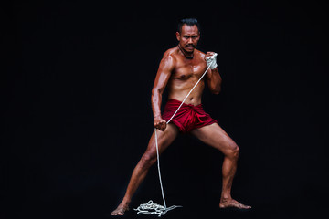 Fototapeta na wymiar Handsome Muscular Man displays ancient Asian traditional martial arts, Thai Boxing or Muay Thai