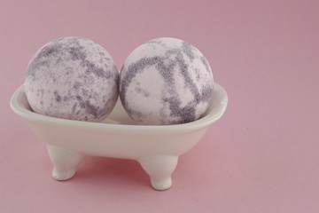 Lavender bath bombs in a ceramic bath on a  pink background. natural vegan organic body cosmetics