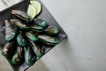 Ousters on black square plate with lemon. Concept of seafood and restaurant.