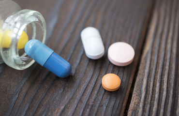 medical tablets poured from a flask on a wooden background
